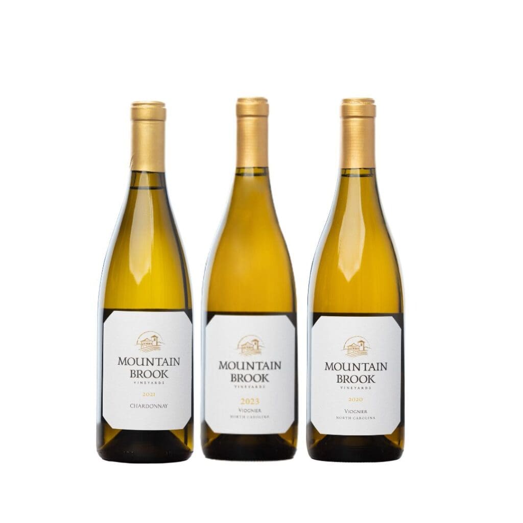 Three bottles of Mountain Brook Vineyards white wine with gold caps labeled Chardonnay and Viognier.